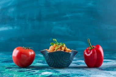 Mavi arka planda bir kase fırında fasulye ile sebzeler. Yüksek kalite fotoğraf