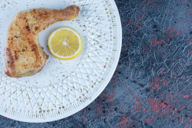 Beyaz bir tabak tavuk budu eti ve bir dilim limon. Yüksek kalite fotoğraf