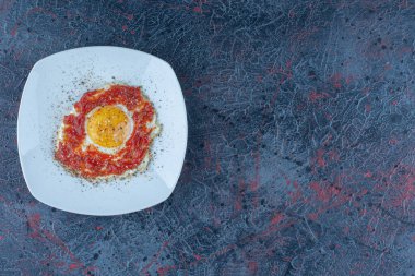 Baharatlı ve domates soslu mavi bir tabak yumurta. Yüksek kalite fotoğraf