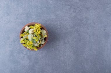 Gri arka planda kurumuş çiçeklerle dolu ahşap kâse manzarası. Yüksek kalite fotoğraf