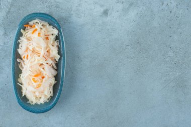 Mavi arka planda tahtadan bir tabakta havuçlu mayalanmış lahana turşusu. Yüksek kalite fotoğraf