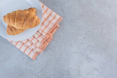 Çizgili masa örtüsü üzerinde beyaz bir tabak lezzetli kruvasan. Yüksek kalite fotoğraf