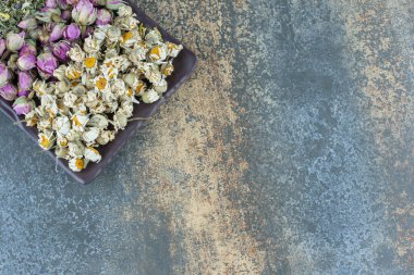 Kurumuş papatya çayı, gül ve yapraklar siyah tabakta. Yüksek kalite fotoğraf