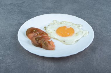 Lezzetli kızarmış yumurta ve beyaz tabakta domates dilimleri. Yüksek kalite fotoğraf