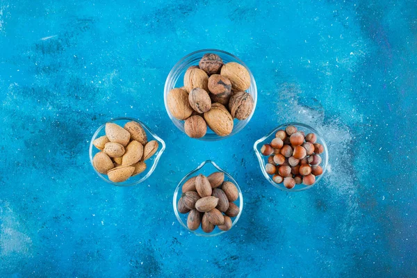 Mavi arka planda, kaselerin üzerinde fındık çeşitleri. Yüksek kalite fotoğraf