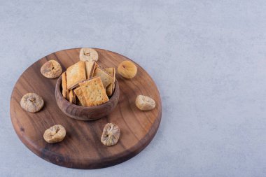 Tahta tahtada bir kase lezzetli çıtır kraker ve kurutulmuş incir. Yüksek kalite fotoğraf