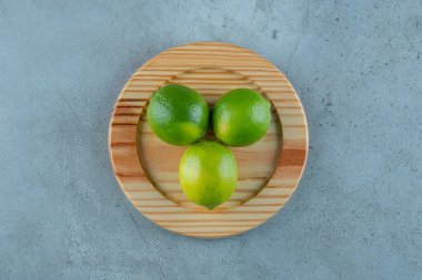 Tahta bir tabakta, mermer zeminde olgunlaşmamış limonlar. Yüksek kalite fotoğraf
