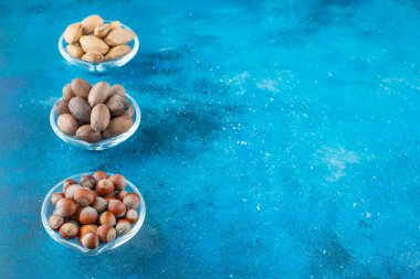 Mavi arka planda, kaselerin üzerinde fındık çeşitleri. Yüksek kalite fotoğraf