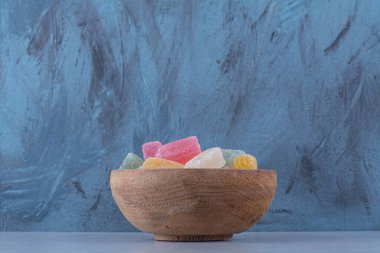 Gri arka planda renkli fasulye şekerleriyle dolu ahşap bir kase. Yüksek kalite fotoğraf