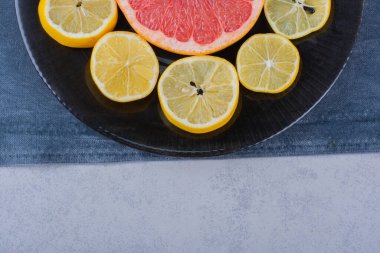 Yuvarlak taze greyfurt dilimleri ve siyah tabakta limonlar. Yüksek kalite fotoğraf