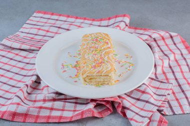 Beyaz tabağa serpiştirilmiş vanilyalı tatlı rulo. Yüksek kalite fotoğraf