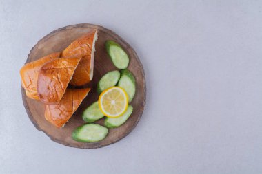 Dilimlenmiş sosisli ekmek, salatalık ve limon, mermer arka planda. Yüksek kalite fotoğraf