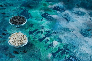 Lezzetli beyaz ve siyah ayçiçeği tohumları cam kaselerde, mavi arka planda. Yüksek kalite fotoğraf