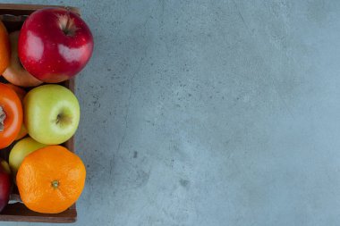 Mermer arka planda, kutuda çeşitli meyveler var. Yüksek kalite fotoğraf