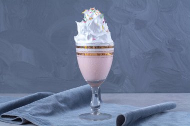Bir bardak milkshake, üzerine şeker serpiştirilmiş krema serpiştirilmiş, mermer arka planda. Yüksek kalite fotoğraf