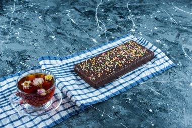 Çay havlusunda bir fincan çay ve çikolatalı waffle, mavi arka planda. Yüksek kalite fotoğraf