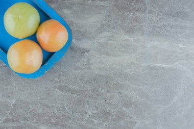 Gri zemin üzerinde mavi ahşap tabakta olgunlaşmamış domateslerin üst görüntüsü. Yüksek kalite fotoğraf