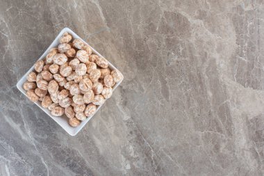 Gri arka planda beyaz kasede karamelli şeker yığını manzarası. Yüksek kalite fotoğraf