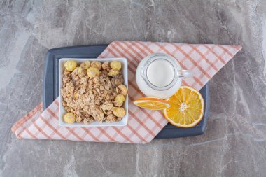 Sağlıklı mısır gevreği ve tahta bir tahtanın üzerinde portakal meyvesi dilimleri olan bir kavanoz süt. Yüksek kalite fotoğraf