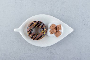Lezzetli çikolatalı çörek ve yapraklı tabakta kremalı mısır gevreği. Yüksek kalite fotoğraf