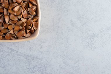 Taş zeminde bir sürü gevrek tohumu olan bej bir kase. Yüksek kalite fotoğraf