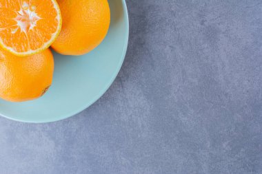 Portakallar tabakta üst üste istiflenmiş, mermer zemin üzerinde. Yüksek kalite fotoğraf