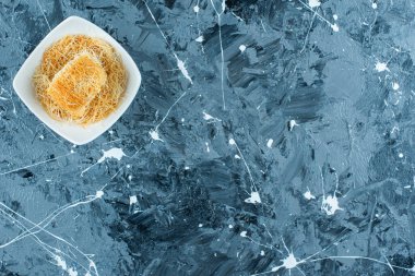 Mavi arka planda, bir kasede Türk tatlısı kadayif. Yüksek kalite fotoğraf