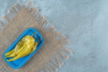 Ahşap bir tabakta, mermer zemin üzerinde konserve acı biber. Yüksek kalite fotoğraf