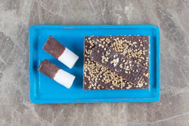 Fındıklı çikolatalı gofret ve ahşap tabakta şekerler, mermer arka planda. Yüksek kalite fotoğraf