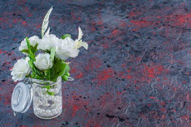 Küçük cam bir kavanoz, içinde güzel inciler ve bir buket çiçek. Yüksek kalite fotoğraf