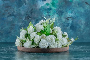 Beyaz çiçekler ahşap bir tabakta, mavi arka planda. Yüksek kalite fotoğraf