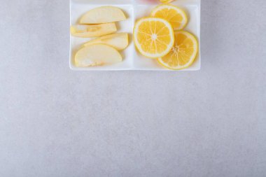 Dilimlenmiş ayva, elma, armut ve limon bir tabakta, mermer zemin üzerinde. Yüksek kalite fotoğraf