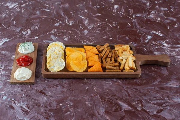 Mermer zemin üzerinde soslu çeşitli cipsler var. Yüksek kalite fotoğraf