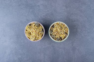 Sağlıklı kuru yapraklar kasede. Gri arka planda kaseyle dolu iki küçük kase. Yüksek kalite fotoğraf