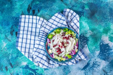 Mavi arka planda, havlunun üzerinde taze, doğranmış çeşitli sebzelerden oluşan ahşap bir tabak. Yüksek kalite fotoğraf