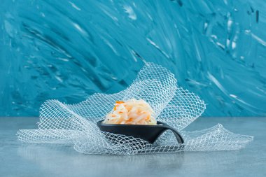 Mavi arka planda, tül üzerinde bir kaşıkta mayalanmış lahana turşusu. Yüksek kalite fotoğraf