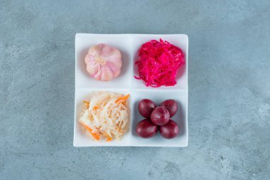 Mermer zemin üzerinde, bir tabakta çeşitli mayalanmış sebzeler. Yüksek kalite fotoğraf