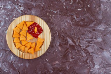 Ahşap tabakta ketçap kaplı koni cipsleri mermer arka planda. Yüksek kalite fotoğraf