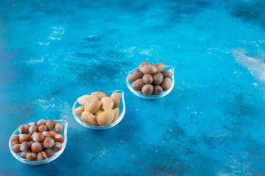 Mavi arka planda, kaselerin üzerinde fındık çeşitleri. Yüksek kalite fotoğraf