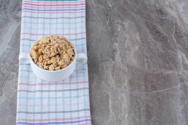 Masa örtüsü üzerinde lezzetli, sağlıklı mısır gevreğiyle dolu beyaz bir kase. Yüksek kalite fotoğraf