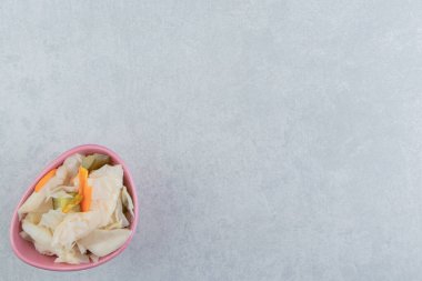 Mermer arka planda, kâsede lezzetli sebze turşusu. Yüksek kalite fotoğraf