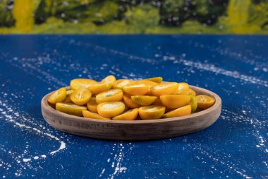 Mermer zemin üzerinde dilimlenmiş tahtadan bir tabak kumkuat meyvesi. Yüksek kalite fotoğraf