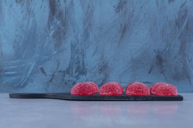 Gri arka planda kırmızı şekerli jöle şekerlerle dolu siyah bir tahta. Yüksek kalite fotoğraf