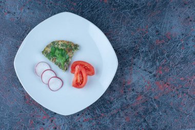 Mavi bir tabak omlet ve dilimlenmiş turpla dilimlenmiş domates. Yüksek kalite fotoğraf