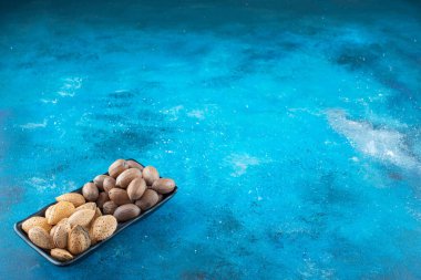 Fındık ve badem bir kasede, mavi arka planda. Yüksek kalite fotoğraf