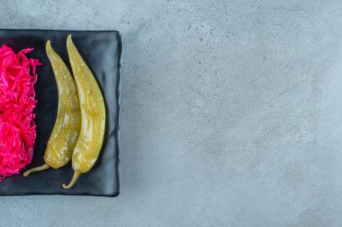 Mavi arka planda plastik bir tabakta mayalanmış biber ve lahana turşusu. Yüksek kalite fotoğraf