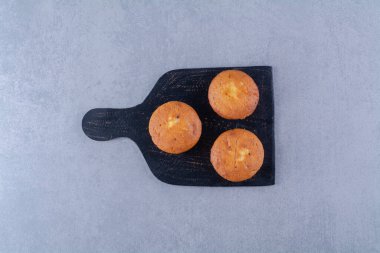 Üç tatlı taze kekten oluşan siyah ahşap bir tahta. Yüksek kalite fotoğraf