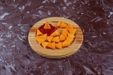 Ahşap tabakta ketçap kaplı koni cipsleri mermer arka planda. Yüksek kalite fotoğraf