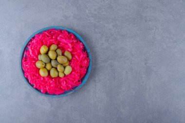 Mavi ahşap tahtada marine edilmiş yeşil zeytinli pembe lahana turşusu. Yüksek kalite fotoğraf