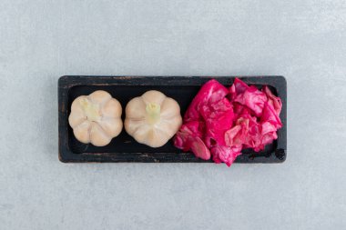 Tahtada, mermer zemin üzerinde sarımsak ve turşulu kırmızı lahana var. Yüksek kalite fotoğraf